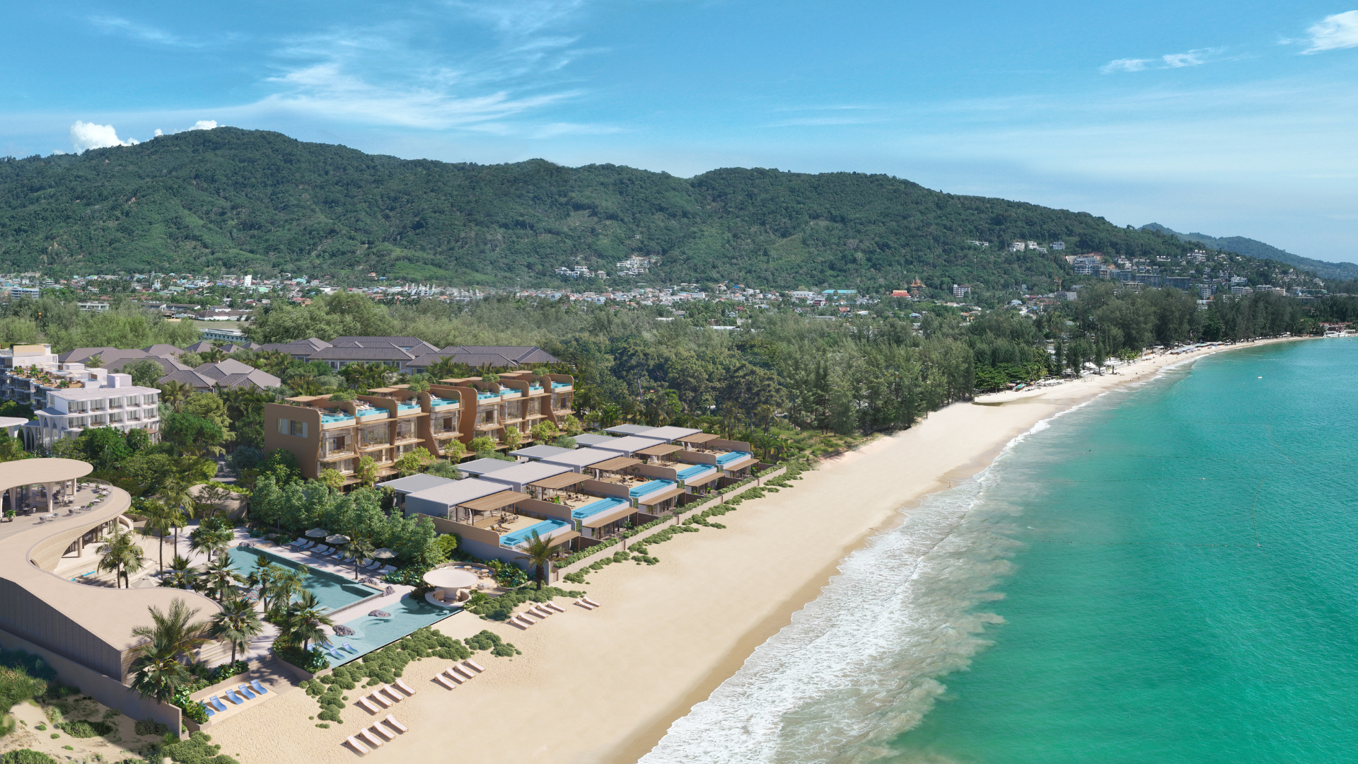 Banyan Tree Beach Residences Mazu - A coastal luxury property in Phuket with modern buildings is nestled between a hillside and a sandy beach with clear blue water, under a cloudy sky.