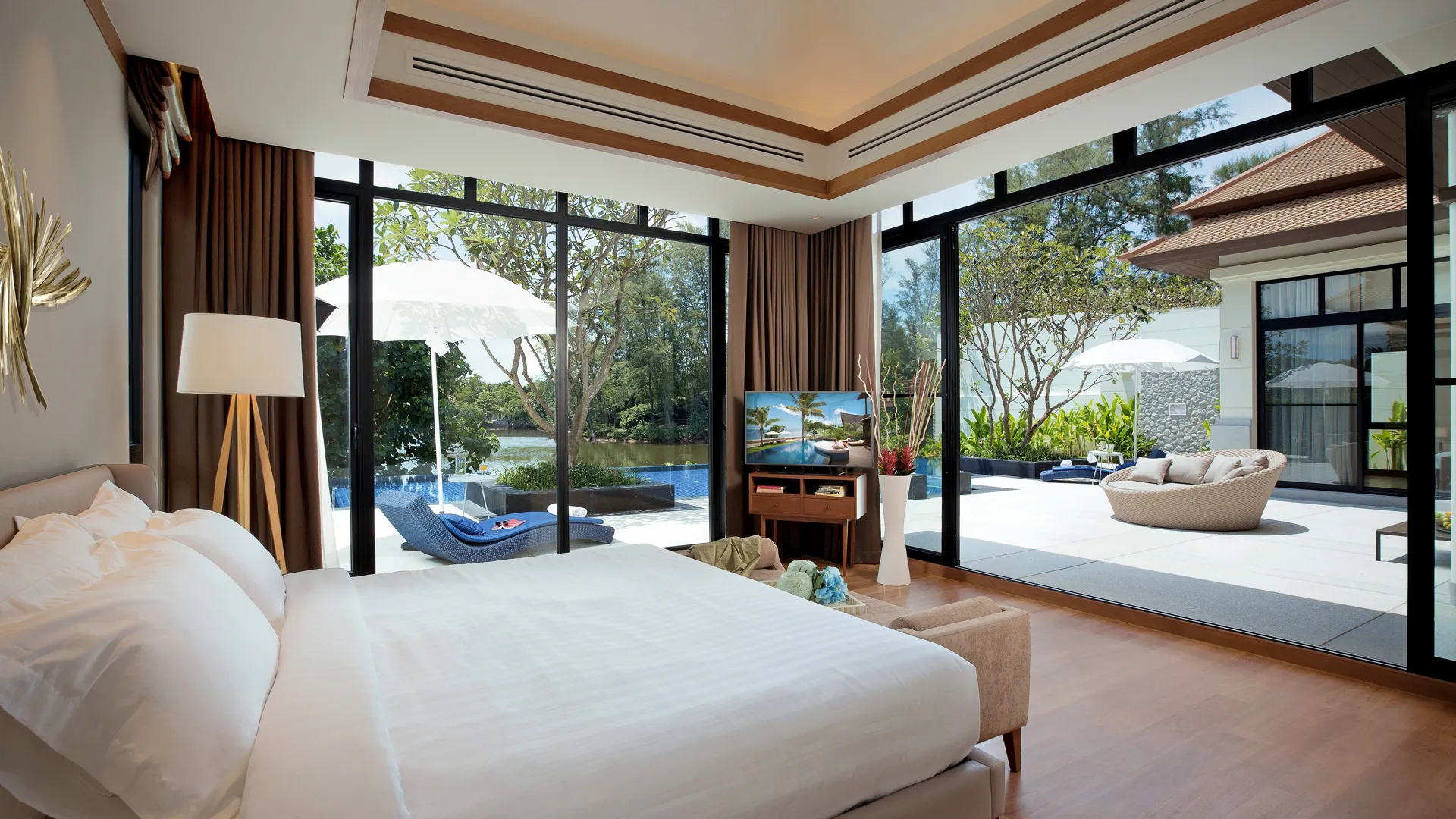 บันยันทรี แกรนด์ เรสซิเดนซ์ แกรนด์ วิลล่า | A spacious hotel room with a large bed facing windows that look out onto a poolside patio.
