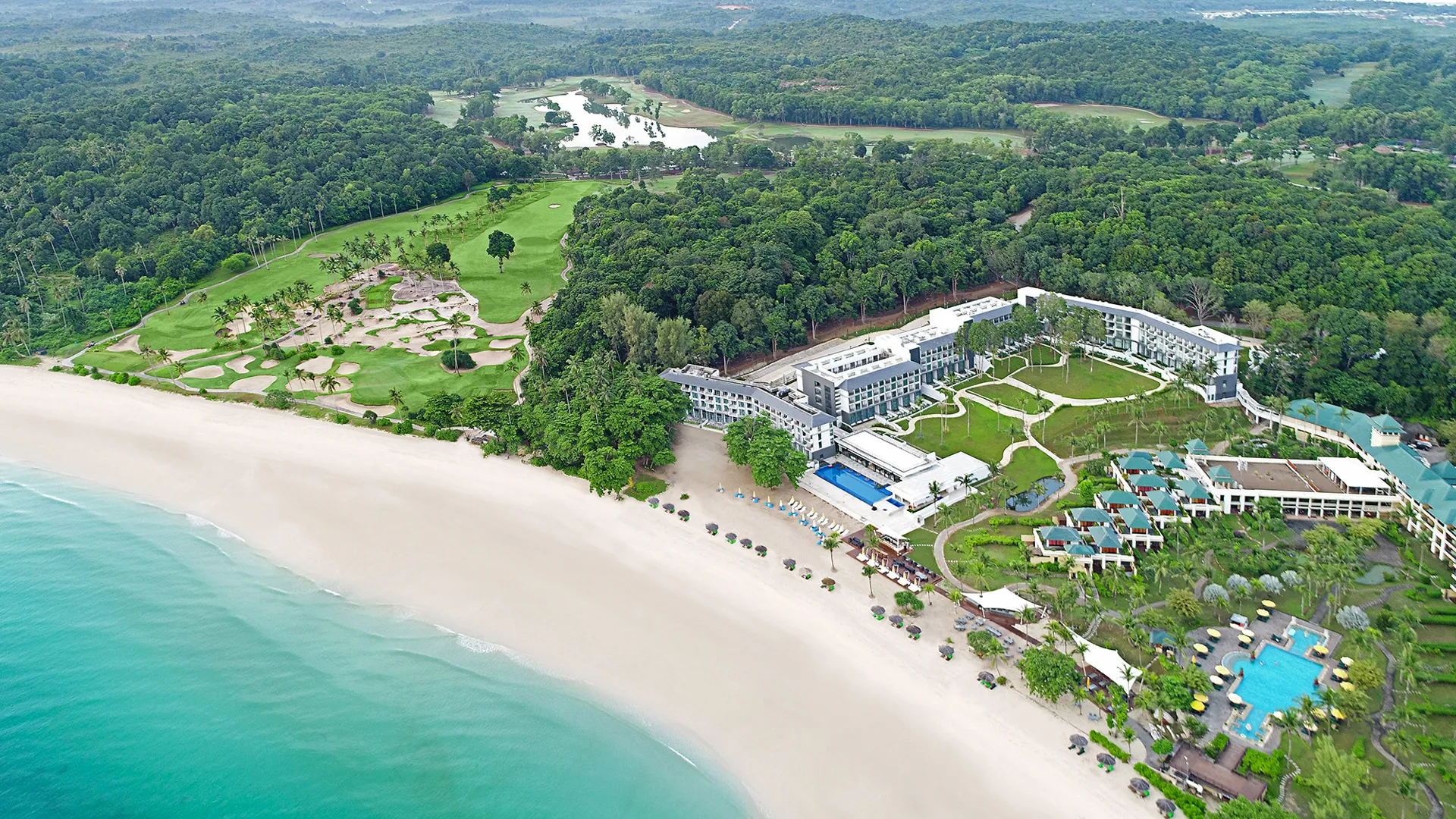 แคสเซีย เรสซิเดนซ์ บินตัน - A coastal resort with pools adjoins a sandy beach, nestled between a lush forest and a manicured golf course.