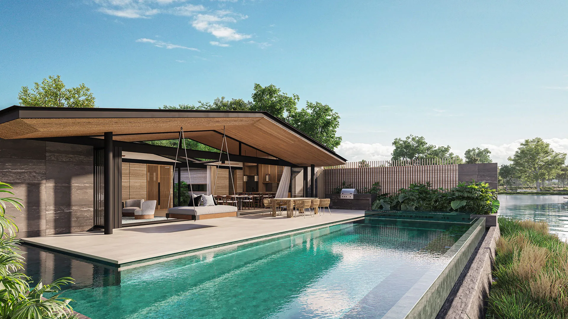 Laguna Lakelands Waterfront Villas - A modern house with an outdoor dining area overlooks a tranquil swimming pool under a clear blue sky.
