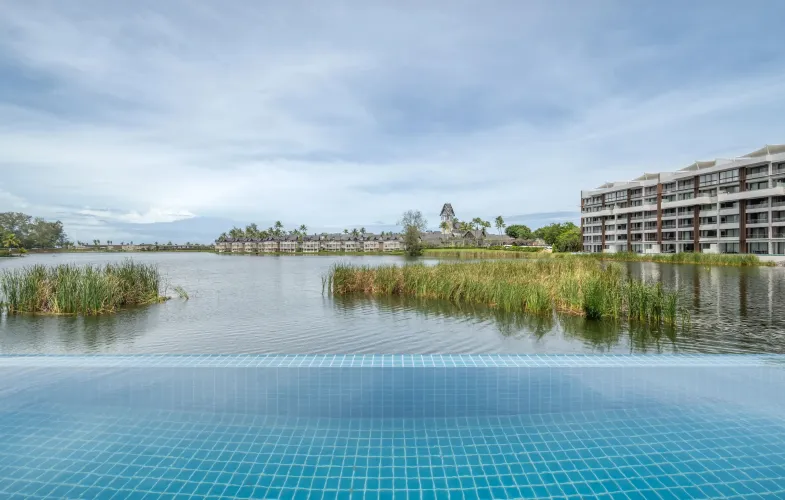 Resort swimming pool surrounded by tropical landscaping at private pool condominium Phuket development